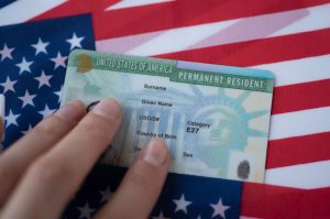 A person holding onto the green card of their permanent resident.