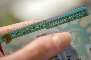 A person holding their green card in his hand.