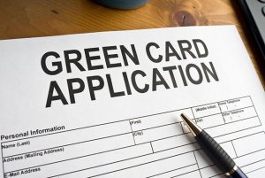 A pen and paper sitting on top of a green card application.